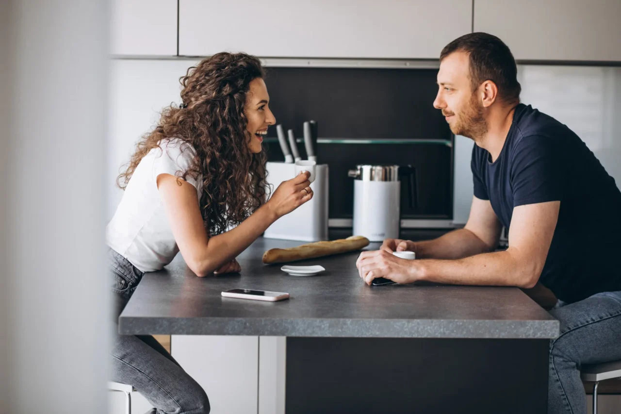 Couple souriant qui discute à l'îlot de sa cuisine